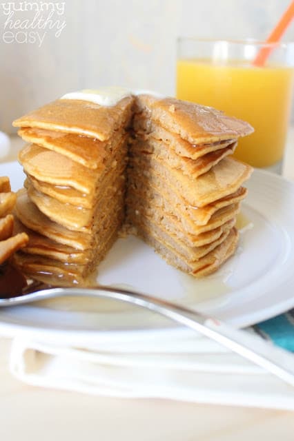 Delicious Pumpkin Pancakes made with healthier ingredients! Stack of pumpkin pancakes with a slice cut out.