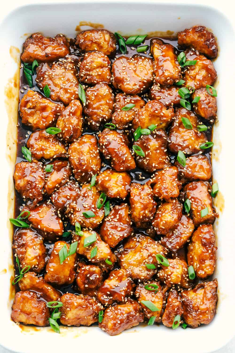 Sesame Chicken is sweet, savory, and perfect for any night of the week. This is so good, it is even better than take out!ย Baked honey sesame chicken in a white dish.