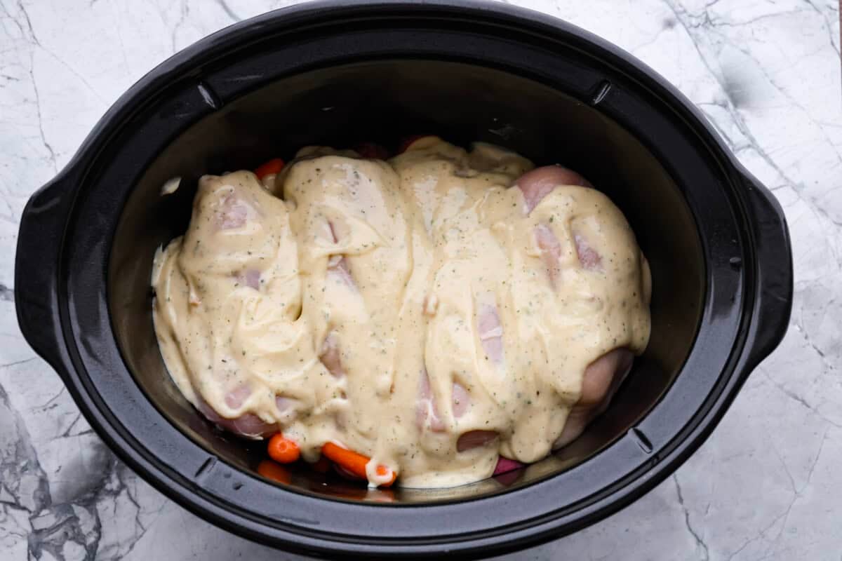 My Slow Cooker Creamy Ranch Chicken takes 10 minutes of prep and uses 6 simple ingredients. It's so good your whole family is going to love it, even your picky eaters! Soup mixture poured over the chicken and veggies in the crockpot.