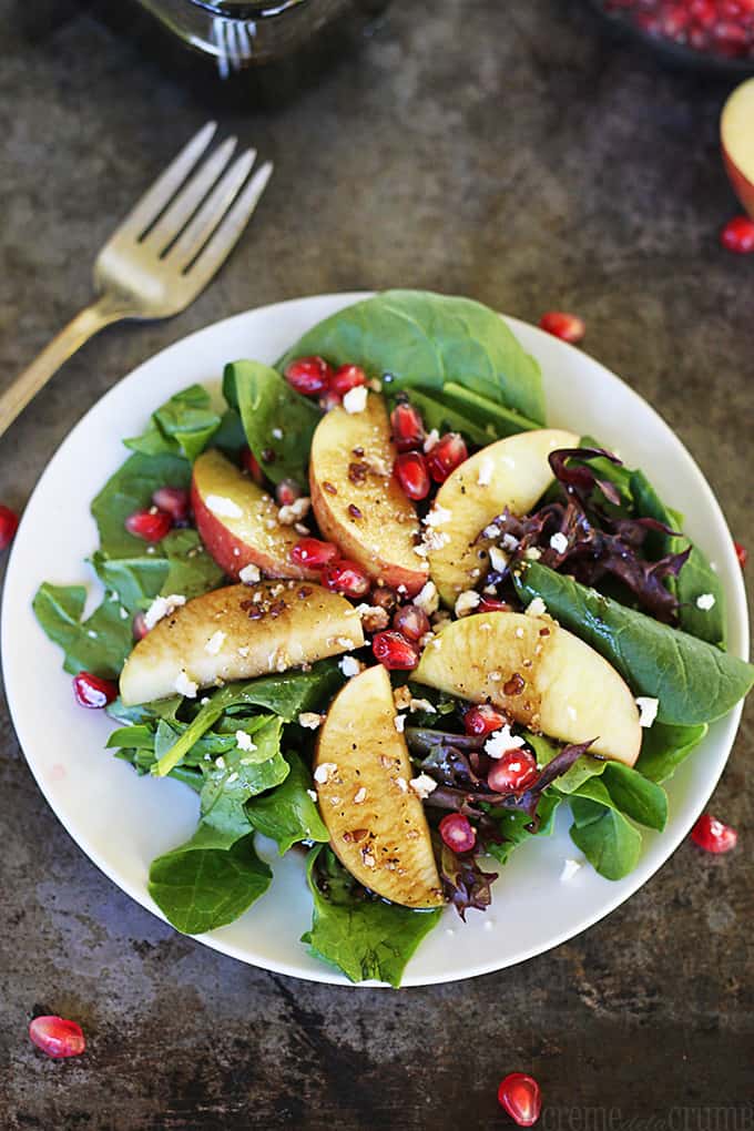 The flavors are so fresh in this salad, you will be adding it to your favorites list! Apple Pomegranate Salad with Honey Balsamic Dressing on a white plate.