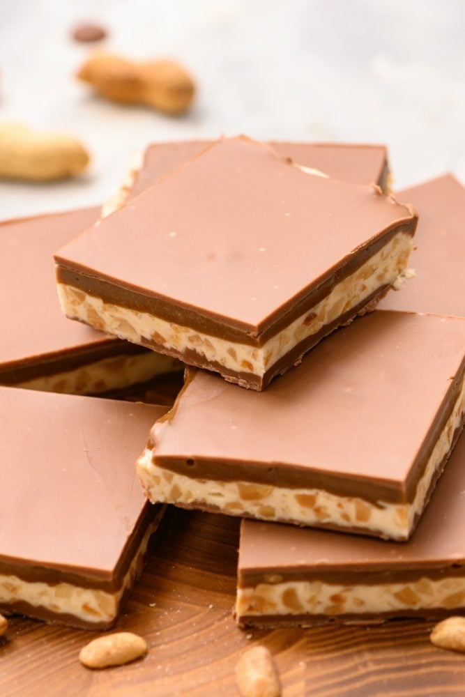 Who says you need to go to the store for a snickers, now you can make them at home whenever the craving hits! Homemade snickers bars stacked on a white counter.