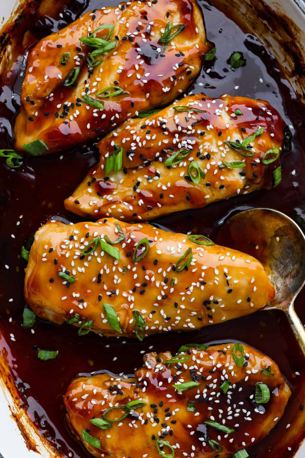 Baked teriyaki chicken is a healthy, delicious dish that comes together in just 45 minutes! The tender, moist chicken is drenched in a sweet and savory teriyaki glaze. Perfect served over some rice and a side of veggies, and the best partโฆ the entire family will love it! Close up shot of baked teriyaki chicken.