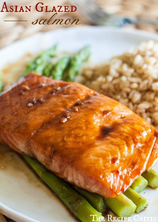A delicious and light lemon pepper salmon that is ready in a matter of minutes! Asian Glazed Salmon over asparagus on a white plate.