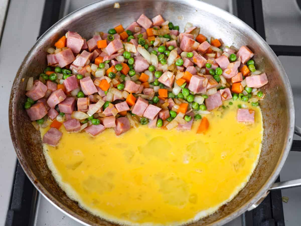 I know how much you guys love my fried rice recipes, and this Ham Fried Rice is a classic! Just toss in leftover rice, ham, and a few simple ingredients, itโs ready in under 30 minutes! Scrambled eggs in the same pan with the ham and veggies, all to one side.