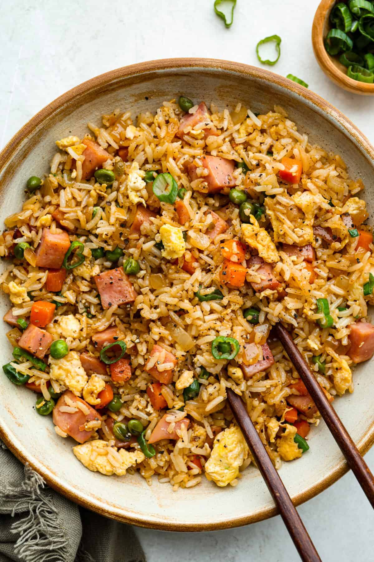I know how much you guys love my fried rice recipes, and this Ham Fried Rice is a classic! Just toss in leftover rice, ham, and a few simple ingredients, itโs ready in under 30 minutes! Plated hame fried rice with chopsticks.