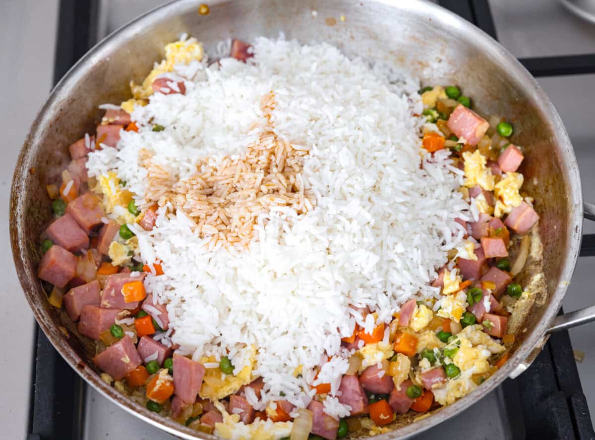 I know how much you guys love my fried rice recipes, and this Ham Fried Rice is a classic! Just toss in leftover rice, ham, and a few simple ingredients, itโs ready in under 30 minutes! White rice and sauces on top of the ham, veggies and eggs.