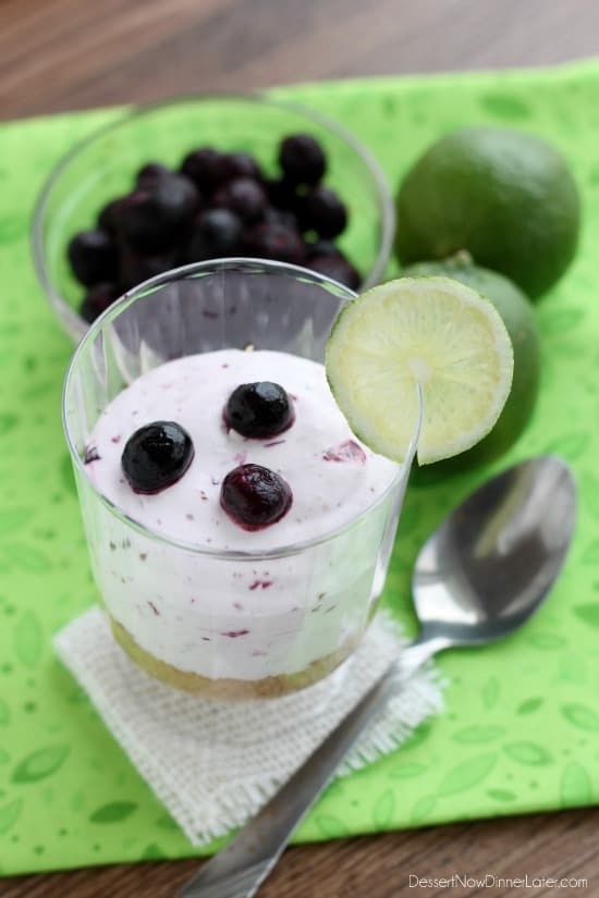 A delicious No Bake Blueberry Lime Cheesecake dessert that the family is sure to love! Blueberry Lime No-Bake Cheesecake Cup with fresh lime and blueberries and a metal fork on the side.