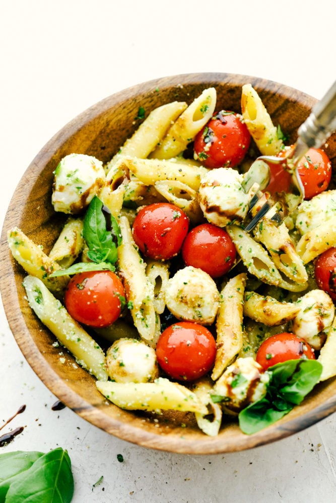 A delicious and flavorful pasta salad that is so easy to throw together! Caprese Pasta Salad in a wood bowl.