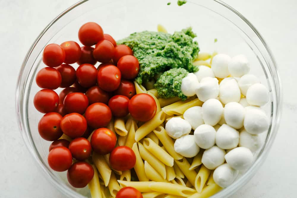 A delicious and flavorful pasta salad that is so easy to throw together! Ingredients for Caprese Pasta Salad in a white bowl.