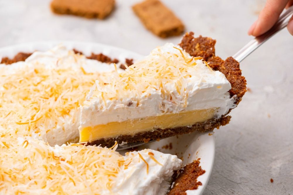 Coconut Cream Key Lime Pie is a fresh, easy to make dessert with a smooth creamy filling and a buttery crunch in the crust. It is beautiful and makes a great sweet treat when entertaining because everyone LOVES it!! Scooping out a slice of key lime pie.