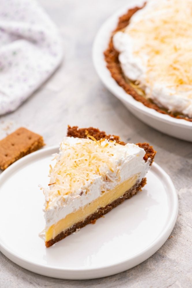 Coconut Cream Key Lime Pie is a fresh, easy to make dessert with a smooth creamy filling and a buttery crunch in the crust. It is beautiful and makes a great sweet treat when entertaining because everyone LOVES it!! Slice of key lime pie on a white plate.