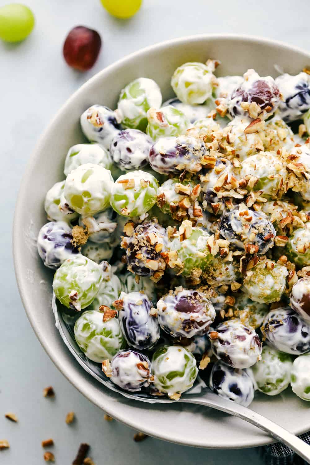 Creamy Grape Saladย is a sweetย and sourย combination with bright green and purpleย grapesย frostedย with silky smooth sour cream and topped with a crunchy pecan. Just imagine big, juicy crisp grapes surrounded by a creamy goodness. Creamy grape salad in a bowl.