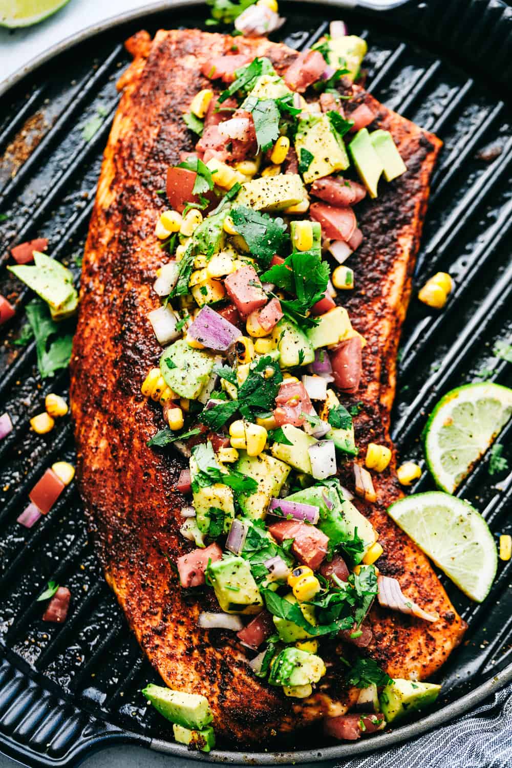 Grilled Salmon with Avocado Salsaย is a tender, juicy grilled salmon, topped with a colorful and flavorfulย combination of avocados, cornย andย tomatoes to make a light and tasty meal. This Salmon is made in minutes for your family!ย Grilled Salmon topped with Avocado Salsa on a grill.