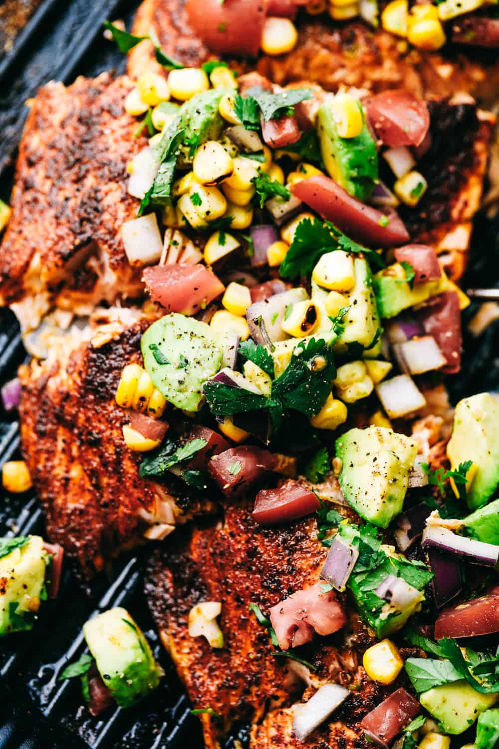 Grilled Salmon with Avocado Salsaย is a tender, juicy grilled salmon, topped with a colorful and flavorfulย combination of avocados, cornย andย tomatoes to make a light and tasty meal. This Salmon is made in minutes for your family!ย Close up of Grilled Salmon with Avocado Salsa.
