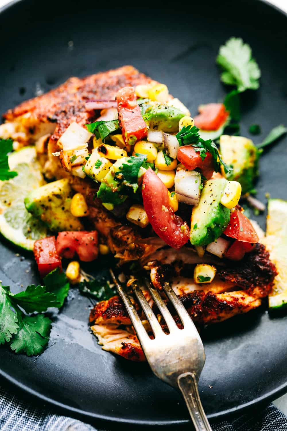 Grilled Salmon with Avocado Salsaย is a tender, juicy grilled salmon, topped with a colorful and flavorfulย combination of avocados, cornย andย tomatoes to make a light and tasty meal. This Salmon is made in minutes for your family!ย Close up of Grilled Salmon with Avocado Salsa