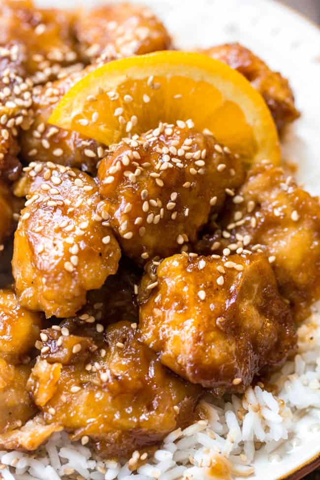 Better than take out Orange Chicken that is baked to perfection and will blow your mind! Orange chicken over rice with a slice of orange.