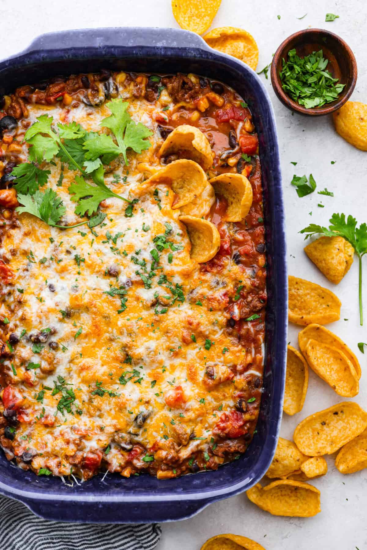 This beef enchilada dip packs all of my favorite things into one dish. It starts with red enchilada sauce, savory beef, olives, and sweet corn smothered in melty cheese. Grab your favorite tortilla chips and get dipping. Overhead shot of beef enchilada dip in baking dish.