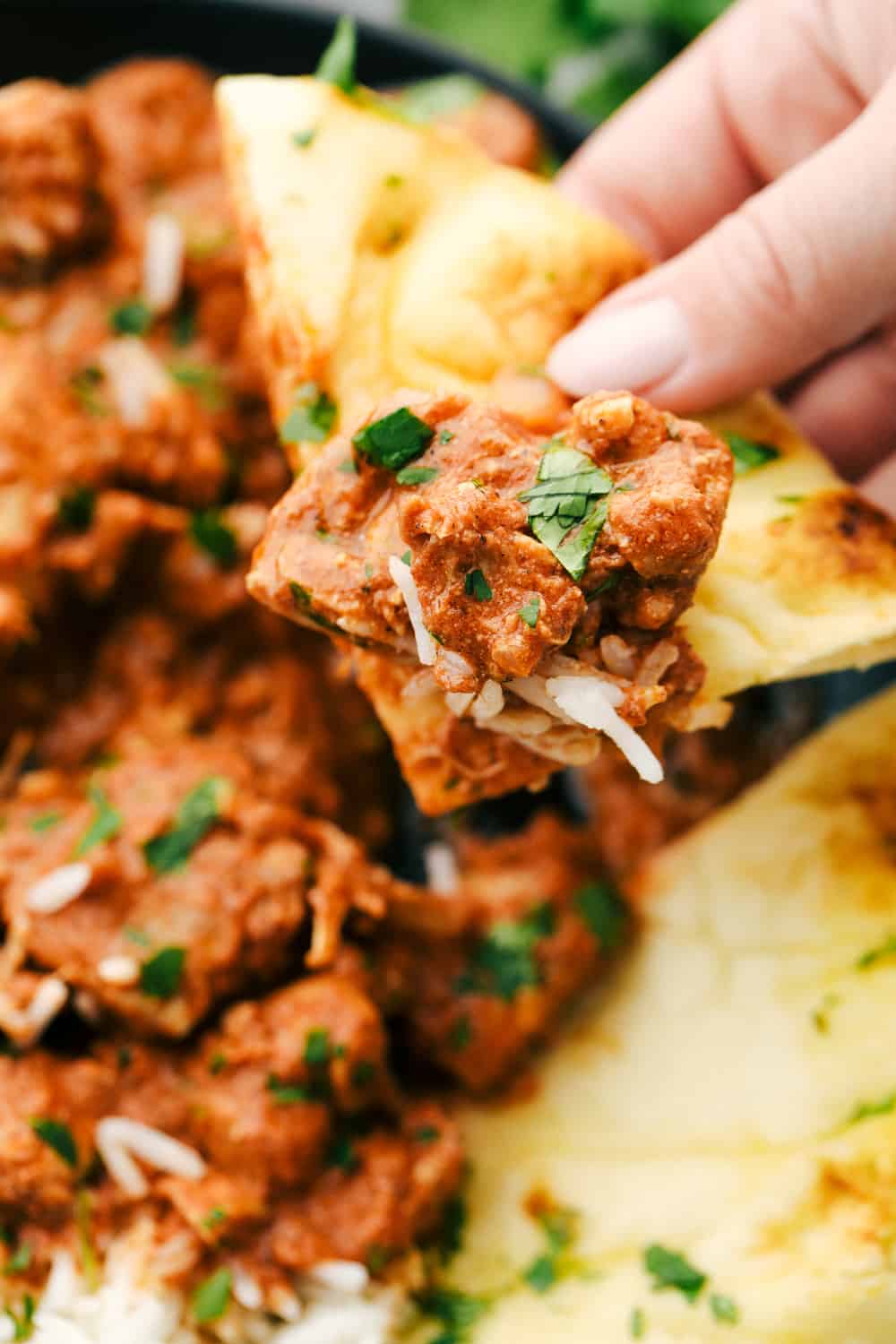Chicken Tikka Masala is an easy, sweet and spicyย sauce thatย is thick, rich and creamy with an intense color of orange and red blend that hasย several spices blendedย together with creamy yogurt covering cubes ofย chicken breasts leaving you with an intense flavor all served over rice. ย Let the slow cooker do all theย work! Chicken Tikka Masala up close dipped in Naan bread.