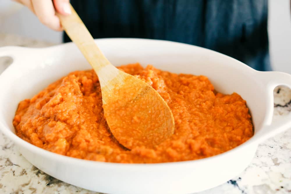 The best sweet potato casserole is smooth and creamy, sprinkled with a brown sugar pecan mixture. It's a sweet and savory side dish that is perfect for the holidays! Adding sweet potato mixture to casserole dish.