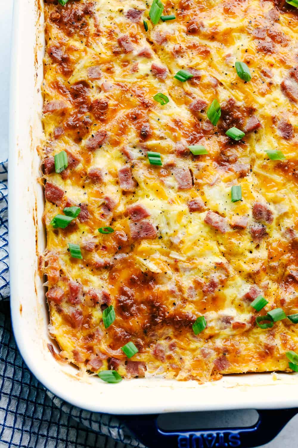 The Best Breakfast Casserole is a thick and creamy egg base with shreddedย potatoes, chunks of ham and flavorful cheese blends that bakes up in no time. Make ahead or enjoy the morning of during the holidays! Close up shot of baked dish.