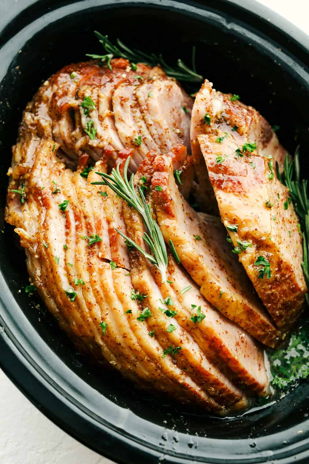 Slow Cooker Honey Garlic Mustard Glazed Ham is the perfect merge of sweet, salty and a touch of spice. This super easy, gorgeously glazed ham will be the talk of the table, with a flavor so divine, it's sure to impress. Garnished Slow cooker ham with a honey, garlic, and mustard glaze.