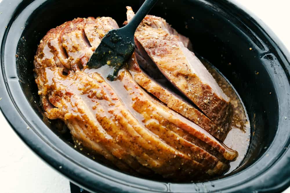 Slow Cooker Honey Garlic Mustard Glazed Ham is the perfect merge of sweet, salty and a touch of spice. This super easy, gorgeously glazed ham will be the talk of the table, with a flavor so divine, it's sure to impress. Basting the ham half way through cooking.