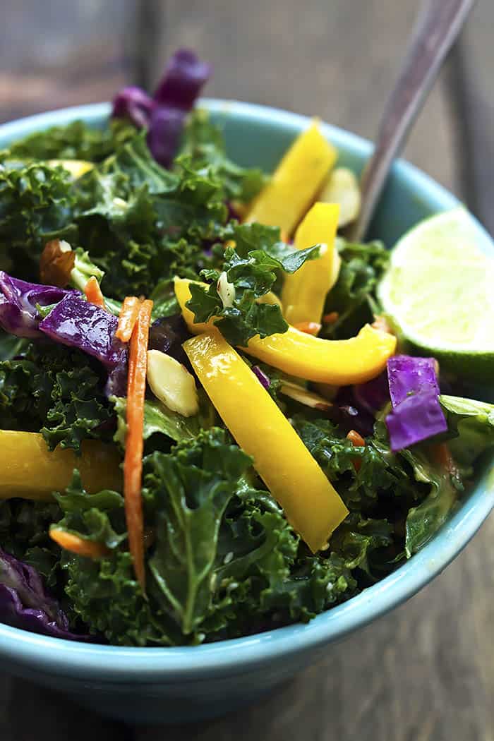 It’s a crunchy Asian kale salad with peppers, cabbage, carrots, and tossed with a creamy peanut ginger dressing. Crunchy Asian kale salad in a blue bowl.