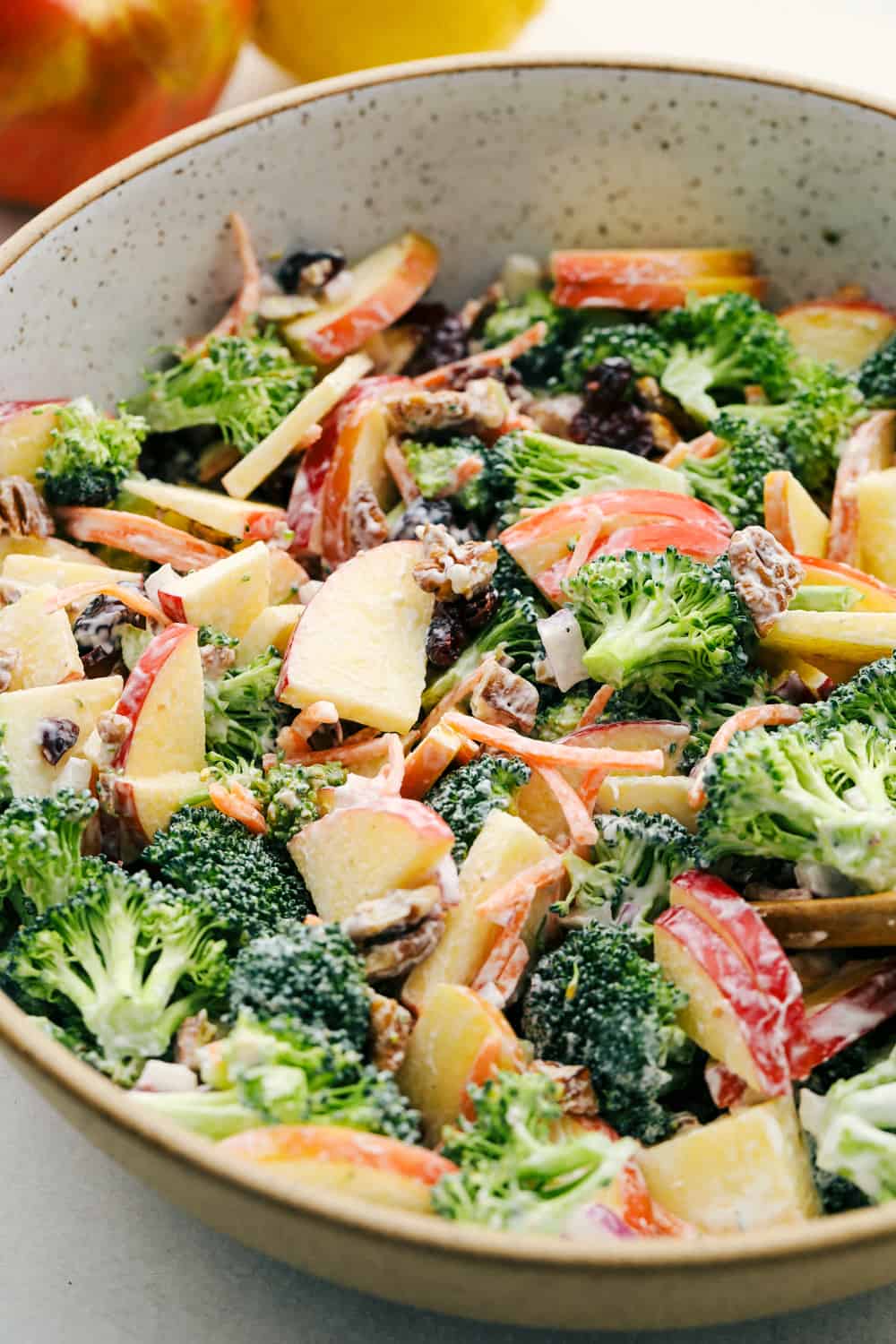 Broccoli, pecans, cranberries, carrots and apples come together to make an amazing salad with delicious flavors and textures. ย The creamy dressing on top makes this salad absolutely incredible! Broccoli apple salad with a tangy dressing in a bowl ready to eat.