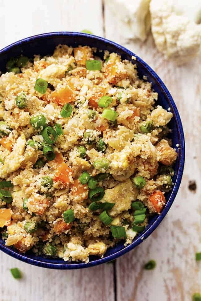 Looks and tastes exactlyย like fried rice! But so much healthier for you! Tastes amazing plain, or would also be great with some ham, chicken or meat added! Cauliflower fried rice in a blue bowl.