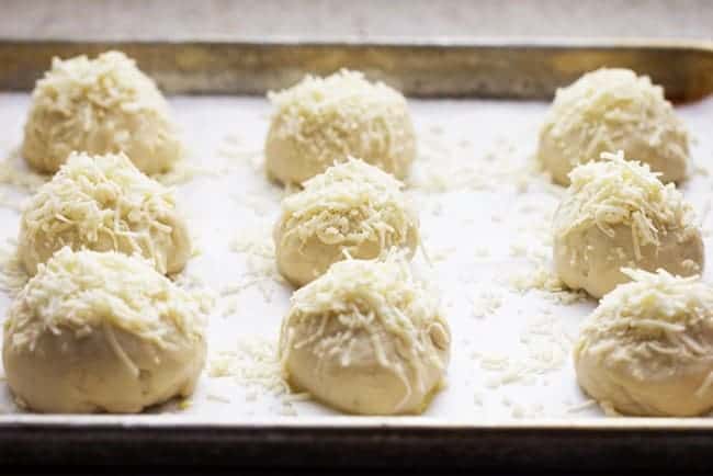 This dough worked perfectly for these rolls. The best part is that the rolls were ready in just 30 minutes! They were soft and fluffy on the inside and perfect on the outside with the cheese. Asiago cheese rolls dough on a pan.