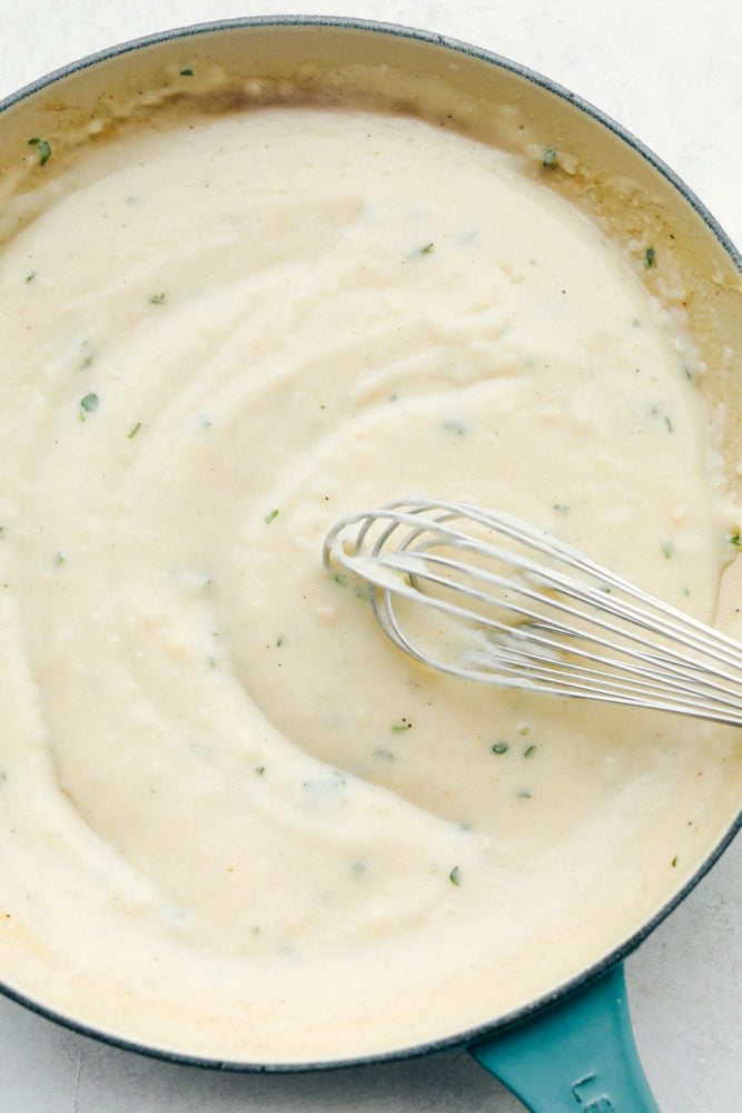 A delicious version of condensed homemade cream of chicken soup! It only takes minutes to make and is a much better alternative to adding chicken-flavored creaminess to your recipes. Top view of a whisk stirring the cream of chicken soup in a skillet.