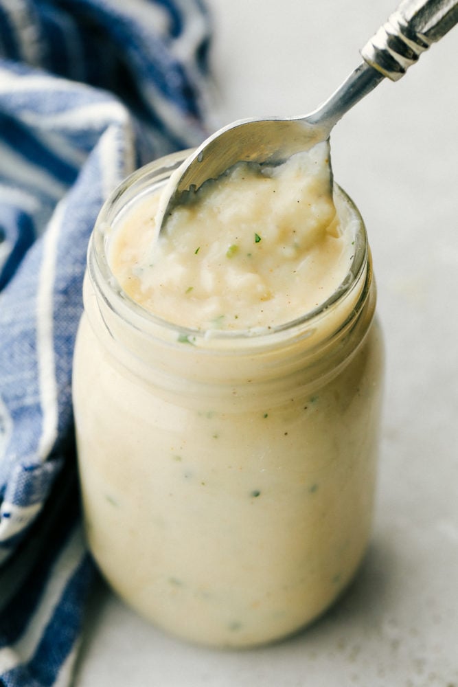 A delicious version of condensed homemade cream of chicken soup! It only takes minutes to make and is a much better alternative to adding chicken-flavored creaminess to your recipes. Close view of homemade cream of chicken soup in a glass jar with a spoon inside the jar.