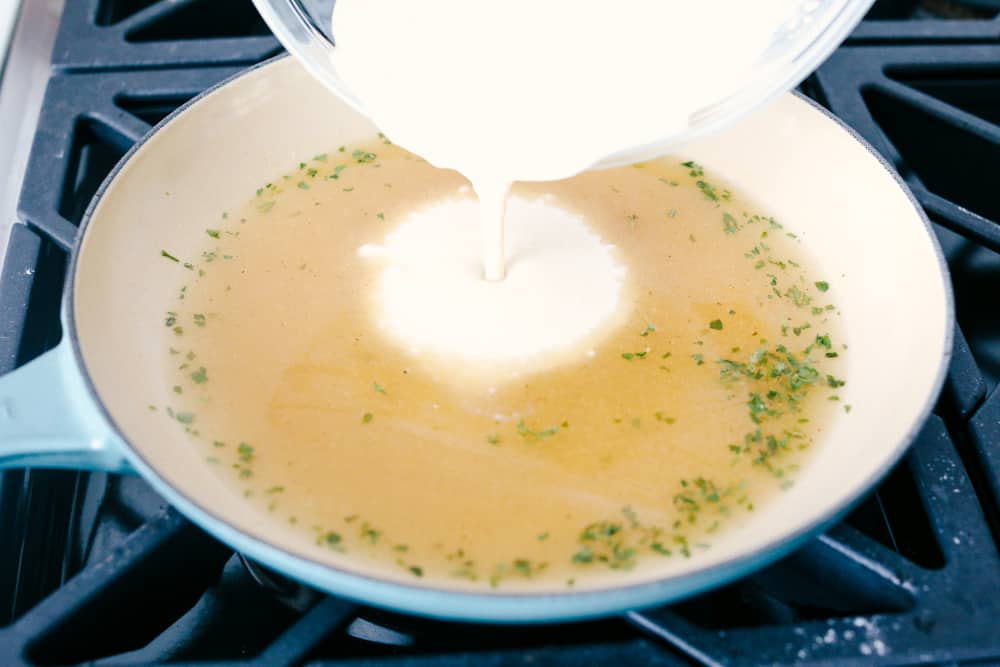 A delicious version of condensed homemade cream of chicken soup! It only takes minutes to make and is a much better alternative to adding chicken-flavored creaminess to your recipes. Milk pouring into a skillet of chicken broth and seasonings.