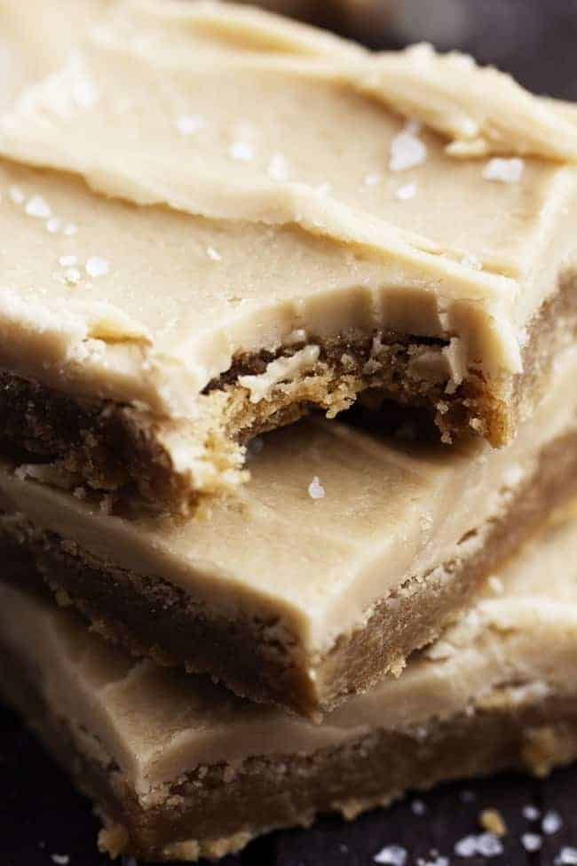 Delicious chewy sugar cookie bars made with brown butter. This adds such amazing flavor and the salted caramel buttercream on top is the best part! Close up on a stack of salted caramel bars