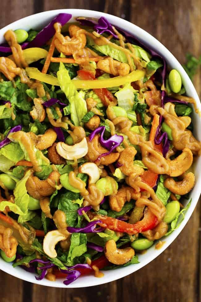 So many delicious vegetables combine in this flavorful and colorful salad! The cashews add a delicious crunch and the Ginger Peanut Sauce on top is amazing! thai salad ready in a white serving dish.