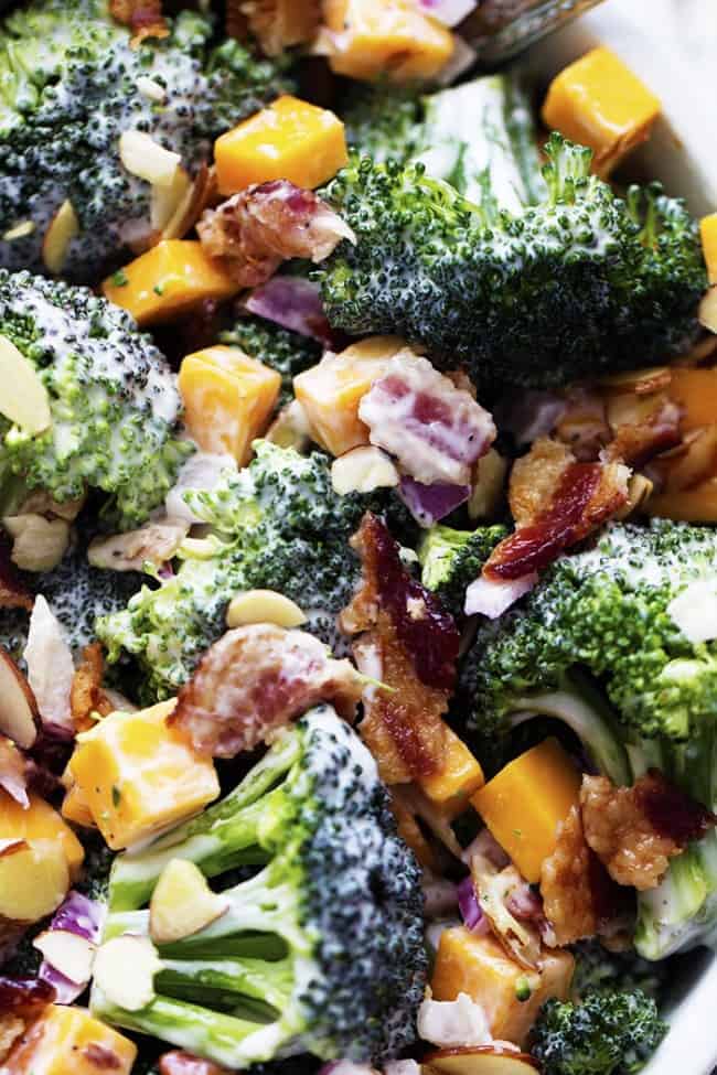 A delicious broccoli salad full of bacon, cheddar, and almonds. The creamy dressing on top is sweet and tangy and AMAZING! creamy broccoli salad in a white bowl.