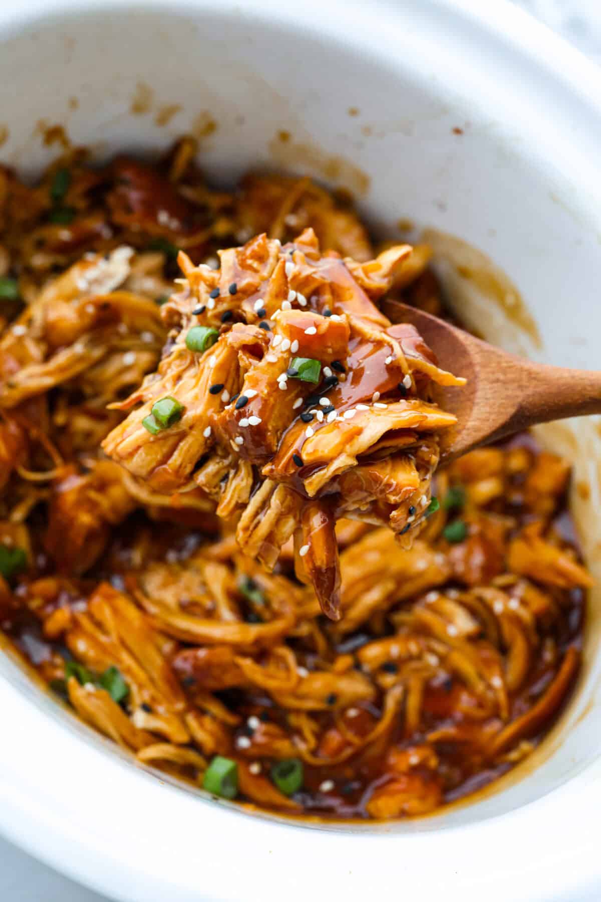 This slow cooker honey teriyaki chicken is so easy to throw together, and the flavor is out of this world! The chicken cooks to perfection and will be one of the best things you'll ever make! Close up shot of a scoop of slow cooker honey teriyaki chicken.