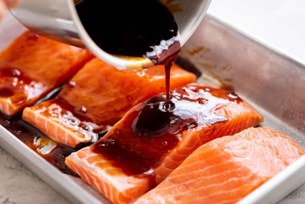 ย ย ย Baked Sesame Teriyaki Salmon is aย five star salmon bakedย with the best homemade sesame teriyaki sauce. This is easily one of the best thingsย that you will eat! salmon with teriyaki sauce drizzled over it