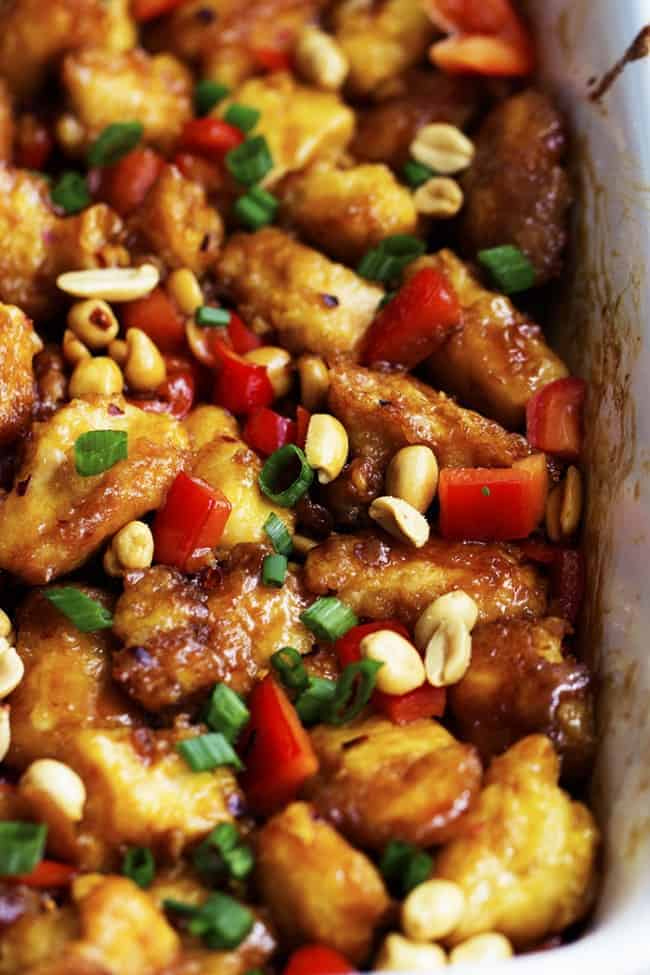 Delicious breaded chicken coatedย in a sweet and spicy sauce with peppers and peanuts hidden throughout. This is WAY better than any takeout you will have! Baked Kung Pao Chicken in a baking pan garnished with peanuts.