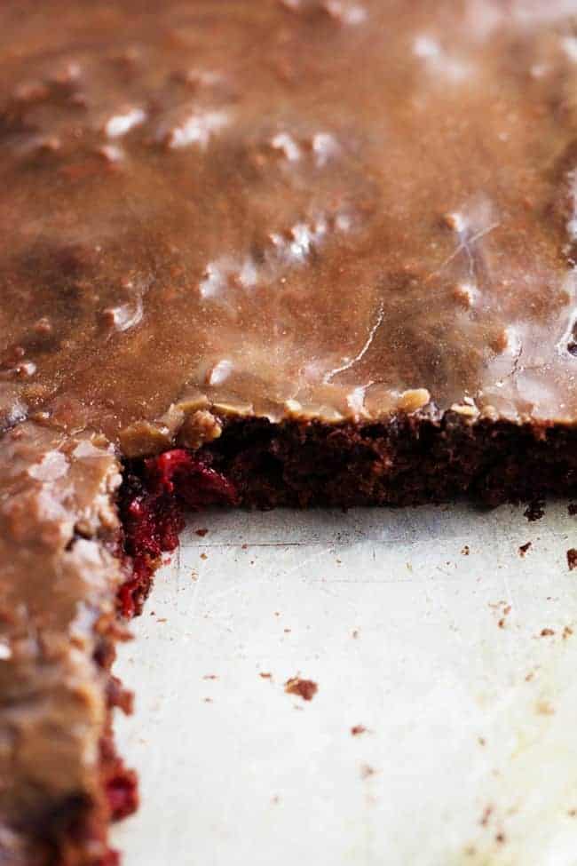 A moist and perfect chocolate sheet cake with cherries hidden inside. This cake is so easy to throw together and the perfect crowd pleaser! Close up on a cut out of chocolate cherry sheet cake.