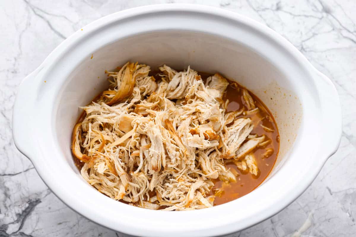 My spicy Slow Cooker Honey Sriracha Chicken is moist, tender, and out-of-this-world delicious with the sweet and spicy sauce! If you love sriracha, you'll love this! Shredded chicken placed back in to the thickened sauce in the crock pot.