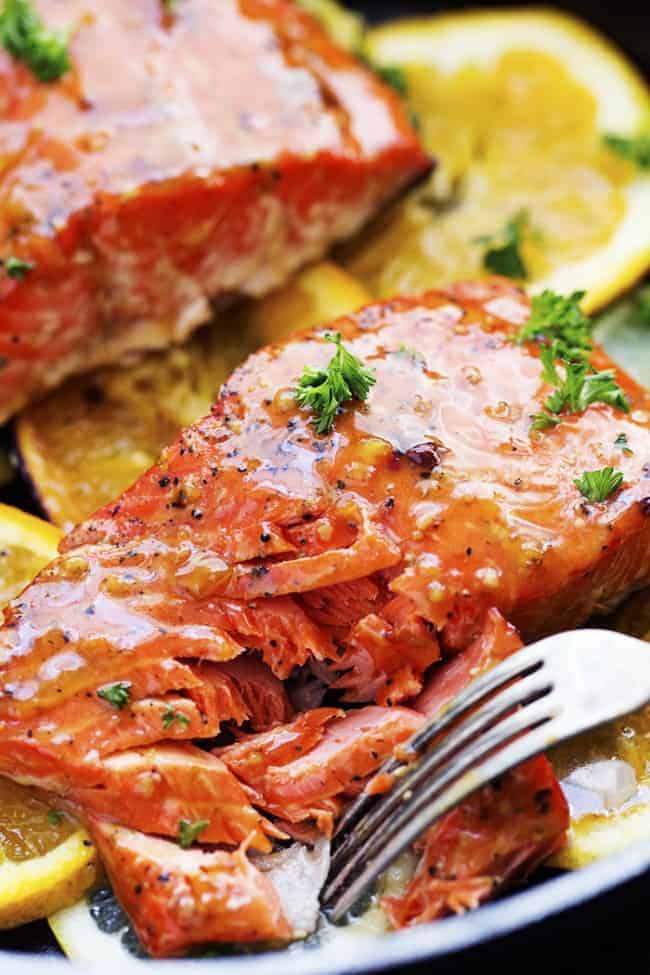 A five starย salmon recipe that gets infused with a lemon, lime and orange marinade. It grills to tender and flaky perfection and has the best sweet and tangy flavor! Pulling apart grilled citrus salmon with a fork close up.
