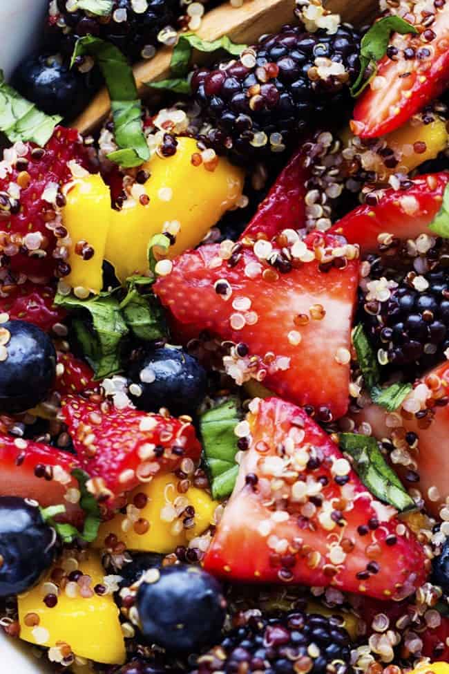 Quinoa, strawberries, blueberries, blackberries, and mango combine in this incredible salad. The fresh fruit and quinoa are glazed with a honey lime dressing and it will be a hit wherever it goes! quinoa fruit salad close up.