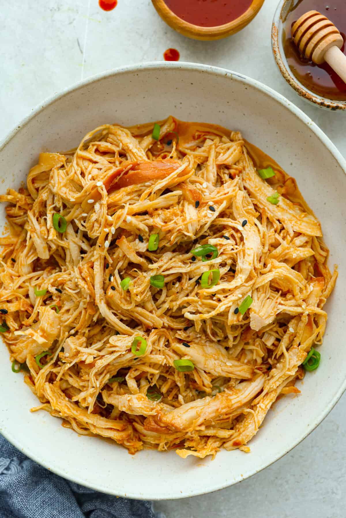 My spicy Slow Cooker Honey Sriracha Chicken is moist, tender, and out-of-this-world delicious with the sweet and spicy sauce! If you love sriracha, you'll love this! Slow cooker honey sriracha chicken in a serving platter.