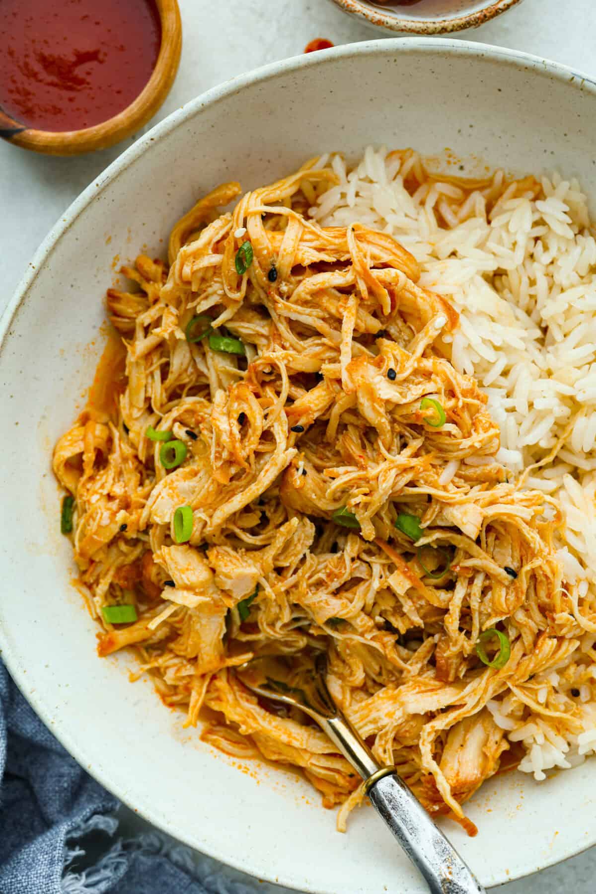 My spicy Slow Cooker Honey Sriracha Chicken is moist, tender, and out-of-this-world delicious with the sweet and spicy sauce! If you love sriracha, you'll love this! Plated slow cooker honey sriracha chicken over rice.