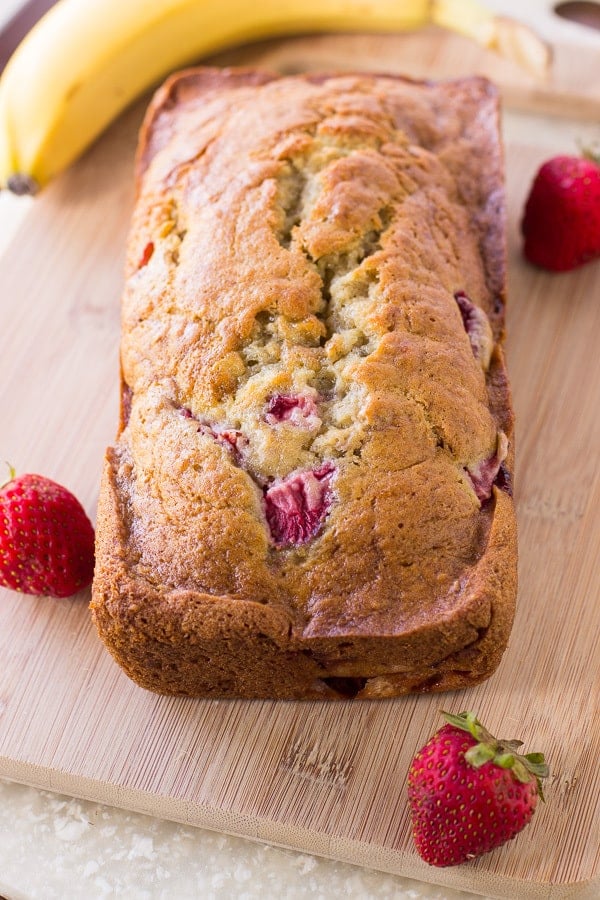 Strawberry Banana Bread is a blend of fresh, juicy strawberries mixed with bananas that make this bread soft and moist in every slice. This isย quick and easy bread that your family is going to love!ย Strawberry Banana Bread loaf on a cutting board