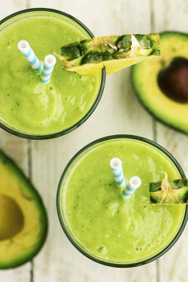 Avocado, pineapple, spinach, kale, coconut and lime come together in this delicious and perfectly smooth smoothie. There are so many delicious things packed into this smoThis delicious and perfectly smooth avocolada smoothie combines avocado, pineapple, spinach, kale, coconut, and lime. It's SOO GOOD that you will want one every day! A top view of a finished smoothie in a glass.