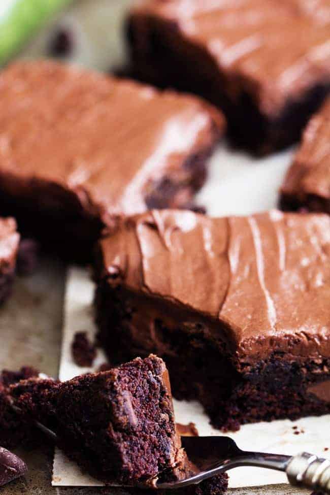 Perfectly moist and chocolatey brownies filled with chocolate chips and topped withย chocolateย frosting. Simple and delicious and you won't even be able to tell that 2 cups of zucchini is hidden inside!ย A bite of double chocolate zucchini brownies on a fork.