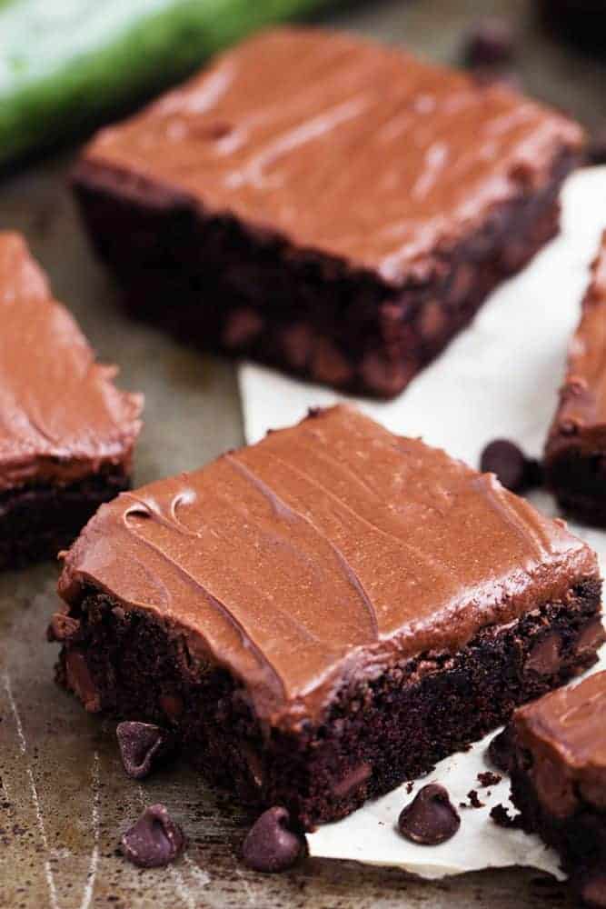 Perfectly moist and chocolatey brownies filled with chocolate chips and topped withย chocolateย frosting. Simple and delicious and you won't even be able to tell that 2 cups of zucchini is hidden inside!ย zucchini brownies close up.