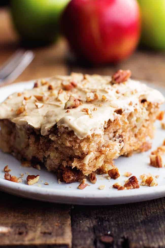 The most tender and moist apple pecan spice cake that you will make. And the brown sugar cream cheese frosting is absolutely delicious! Apple Pecan Spice Cake with Brown Sugar Cream Cheese Frosting side view on a white plate.